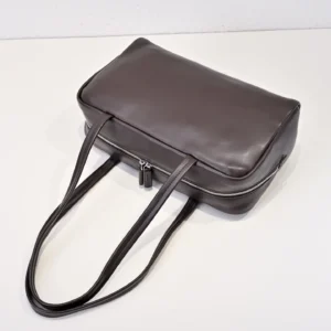 Given the image depicts a dark brown leather tote bag with long straps and a zipper, but no brand or model information is visible, please provide the brand and model for exact alt text creation. If you want, I can generate a generic alt text based on the visible details.