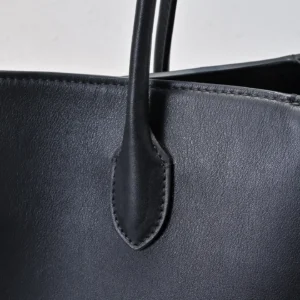Unknown brand black leather handbag close-up of handle and stitching detail