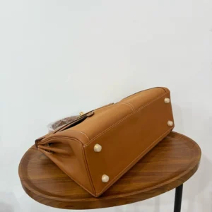 Hermès Birkin 30 tan leather and canvas handbag with gold hardware on wooden table