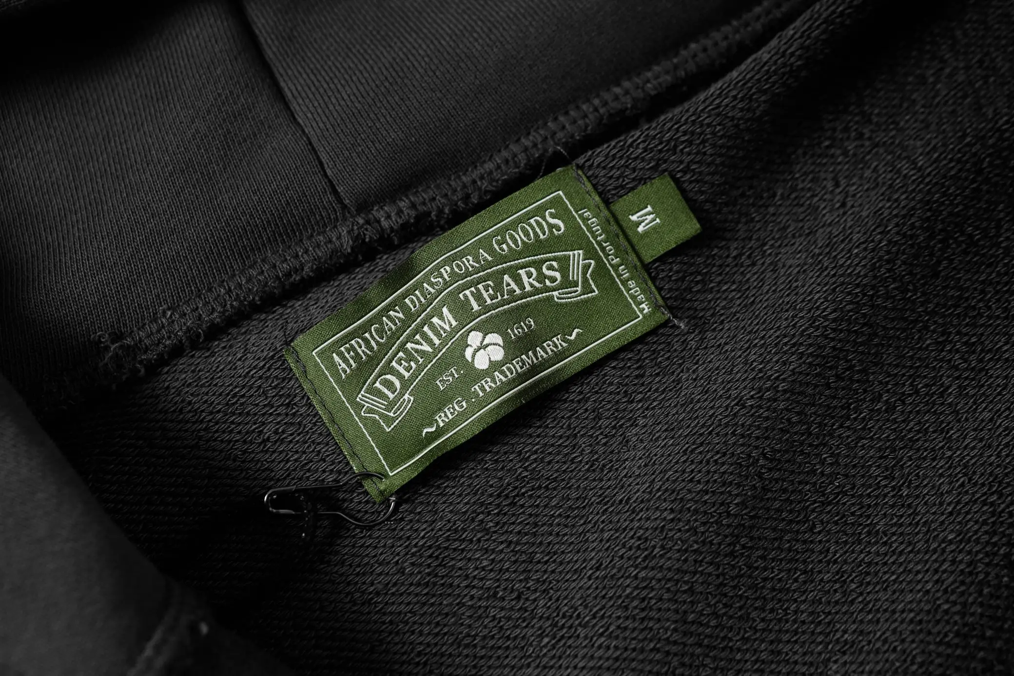 Denim Tears African Diaspora Goods black cotton fabric clothing label with green tag medium size