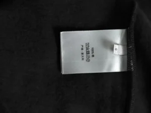 Tag on black fabric showing 100% cotton material and made in Italy with size S label