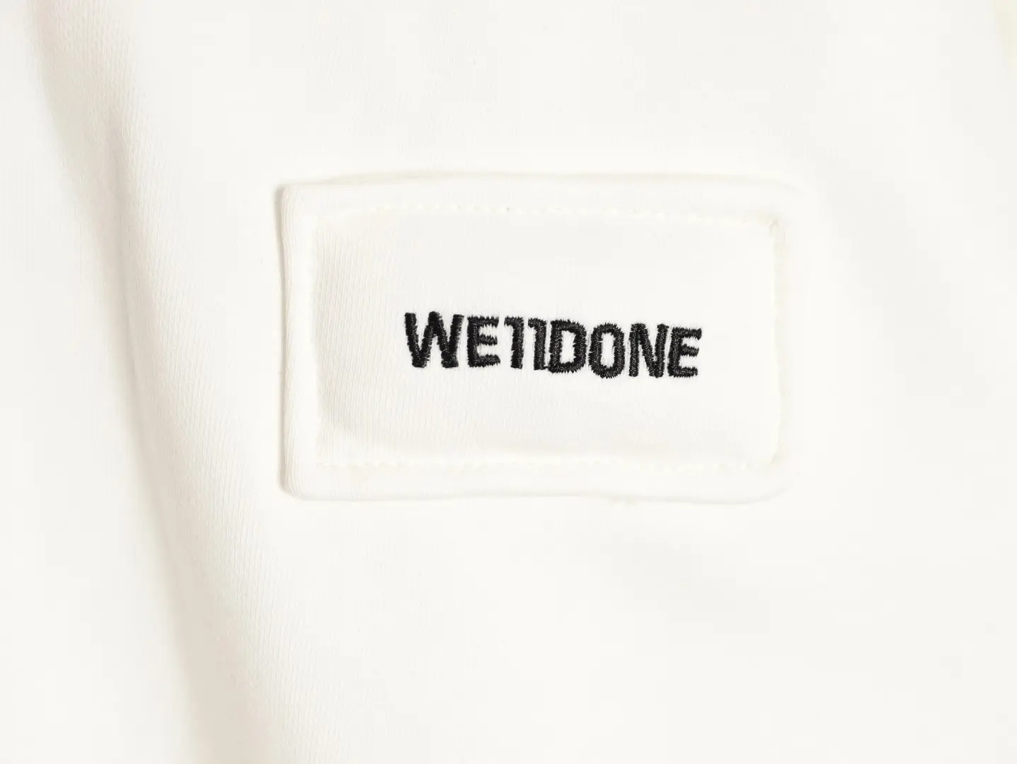 We11done clothing label white cotton fabric with black embroidered logo patch