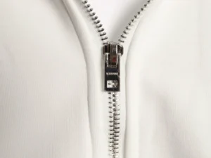 YKK silver metal zipper on white cotton fabric accessory with durable teeth and pull tab mechanism