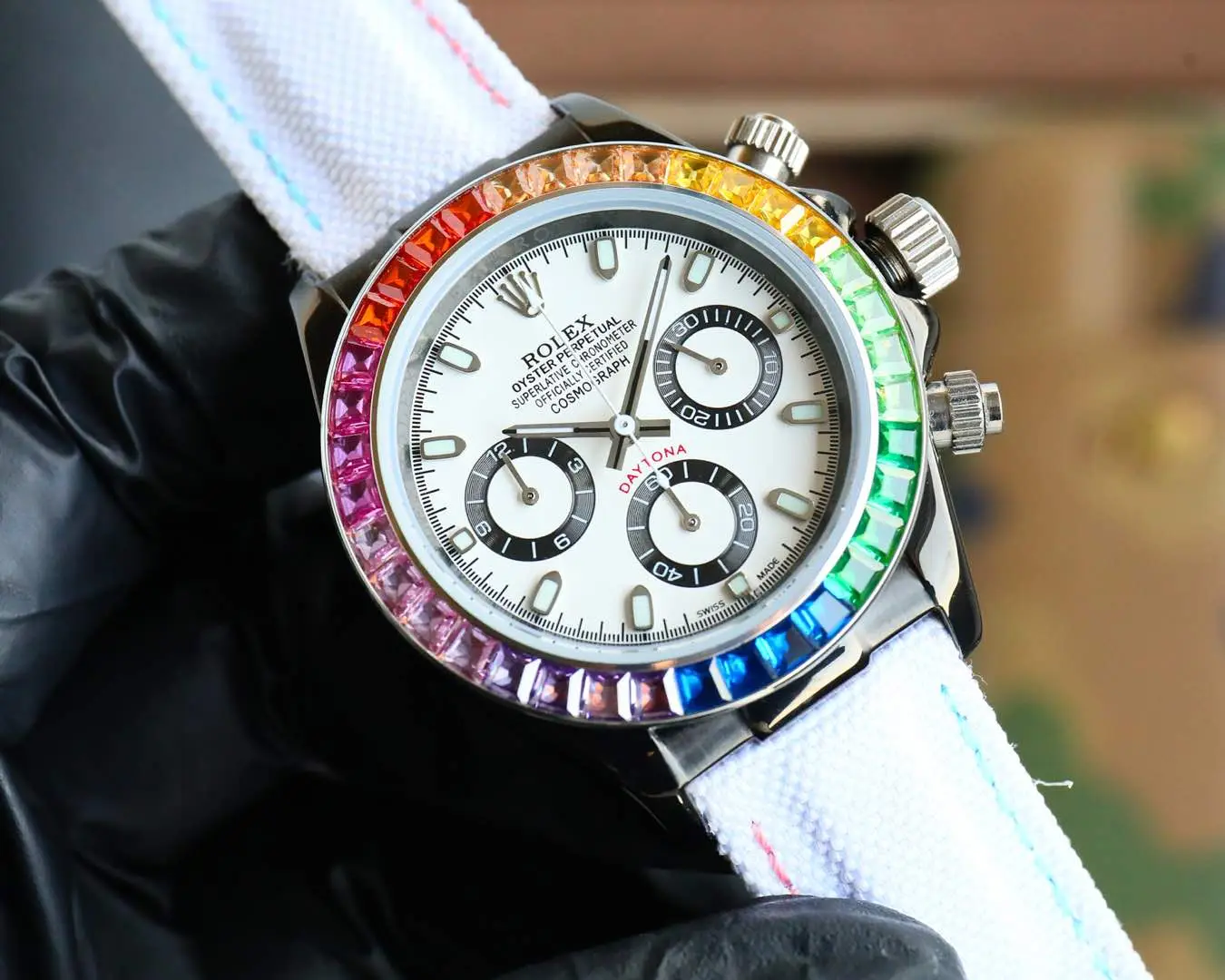 Rolex wristwatch Cosmograph Daytona Rainbow with multicolor bezel and white dial on a white strap.